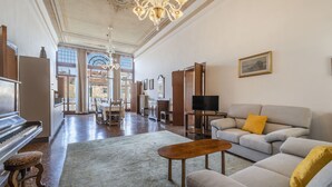 A spacious living room with a grand piano, a sofa set, a television, and a chandelier. - Ca' Magia - Rialto Exclusive Residence by Wonderful Italy (Venice)