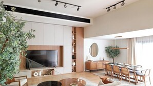 A modern living room with a large TV, a dining area with a table and chairs, and a staircase with boxes. - VESTA - Luxury APT - 3BR - La Mirada (New Cairo City)