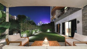 An outdoor seating area with a table and chairs, a candle, and a view of a cityscape at dusk. - VESTA - Luxury APT - 3BR - La Mirada (New Cairo City)
