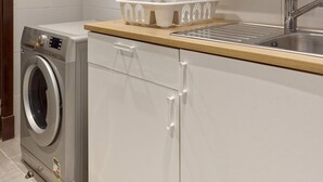 Een moderne keuken met een ingebouwde wasmachine, een spoelbak en witte kastjes.