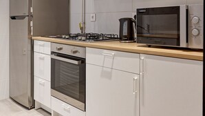 Een moderne keuken met roestvrijstalen apparatuur, witte kastjes en een houten aanrecht.