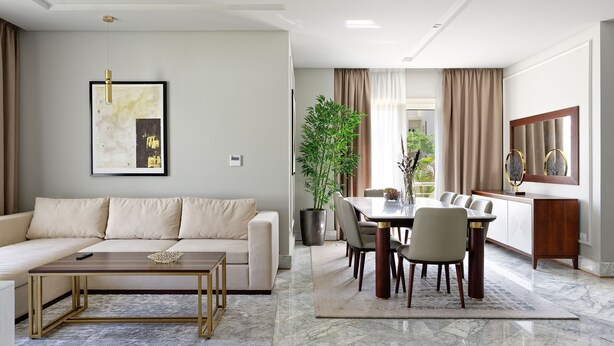 A modern living room with a sofa, coffee table, and dining area with chairs and a table.