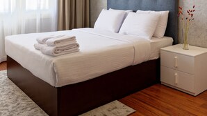 A modern bedroom with a large bed, a nightstand, and a vase of flowers.