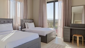 Een moderne slaapkamer met twee bedden, een bureau en een groot raam met gordijnen.