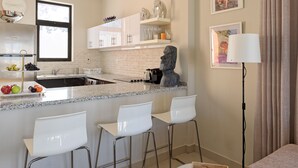 Een moderne keuken met een granieten aanrechtblad, witte barstoelen en een stenen sculptuur.