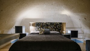 A bedroom with a vaulted ceiling, a bed with a floral headboard, bedside tables, and a wall-mounted TV.