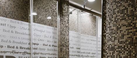 Un baño con pared de azulejos, lavamanos y espejo.