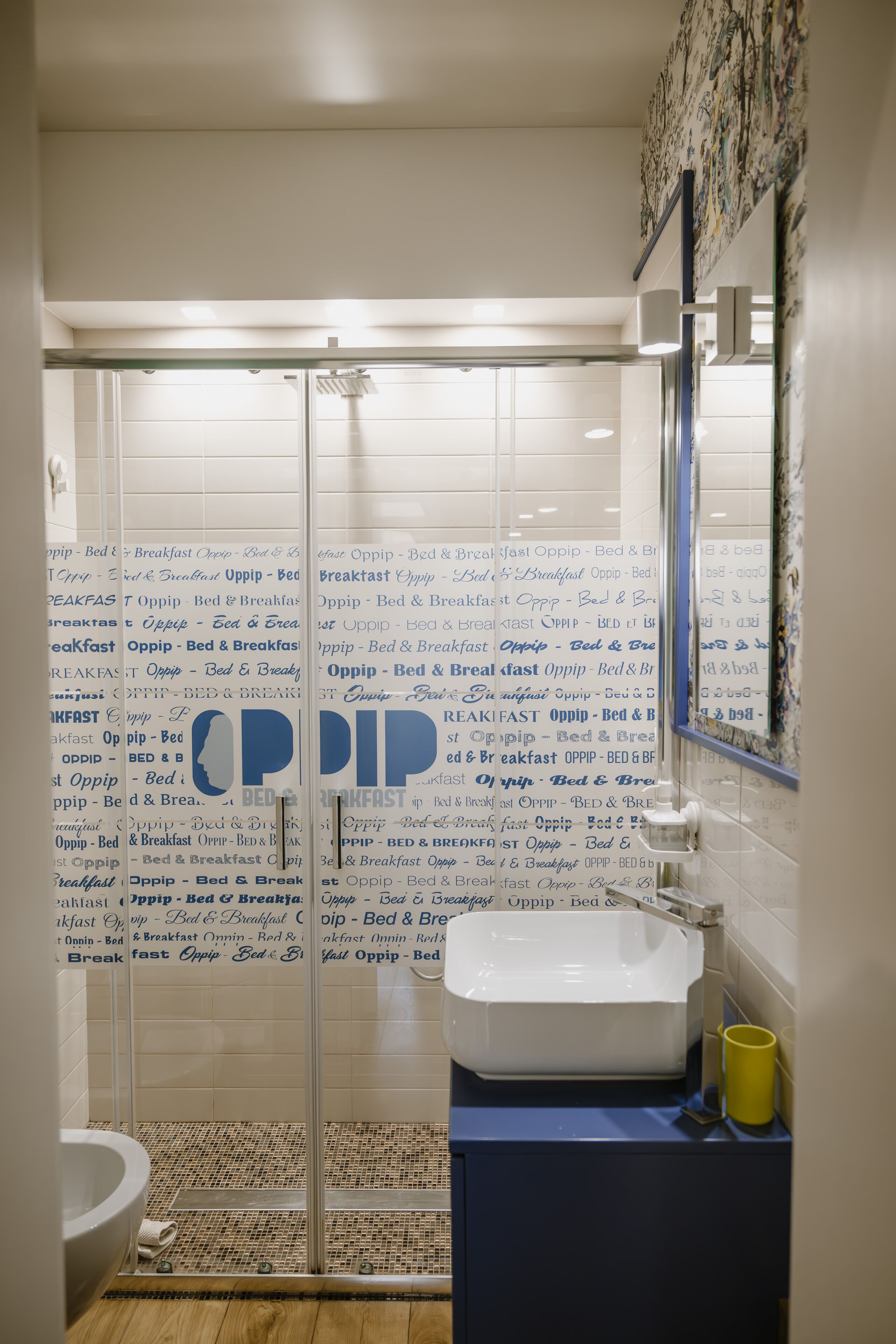 A bathroom with a glass shower enclosure, a white sink, and a mirror.