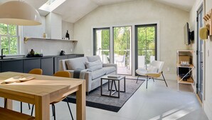 A modern kitchen with a dining area, a sofa, and a TV mounted on the wall. - 9 Academy (Salisbury)