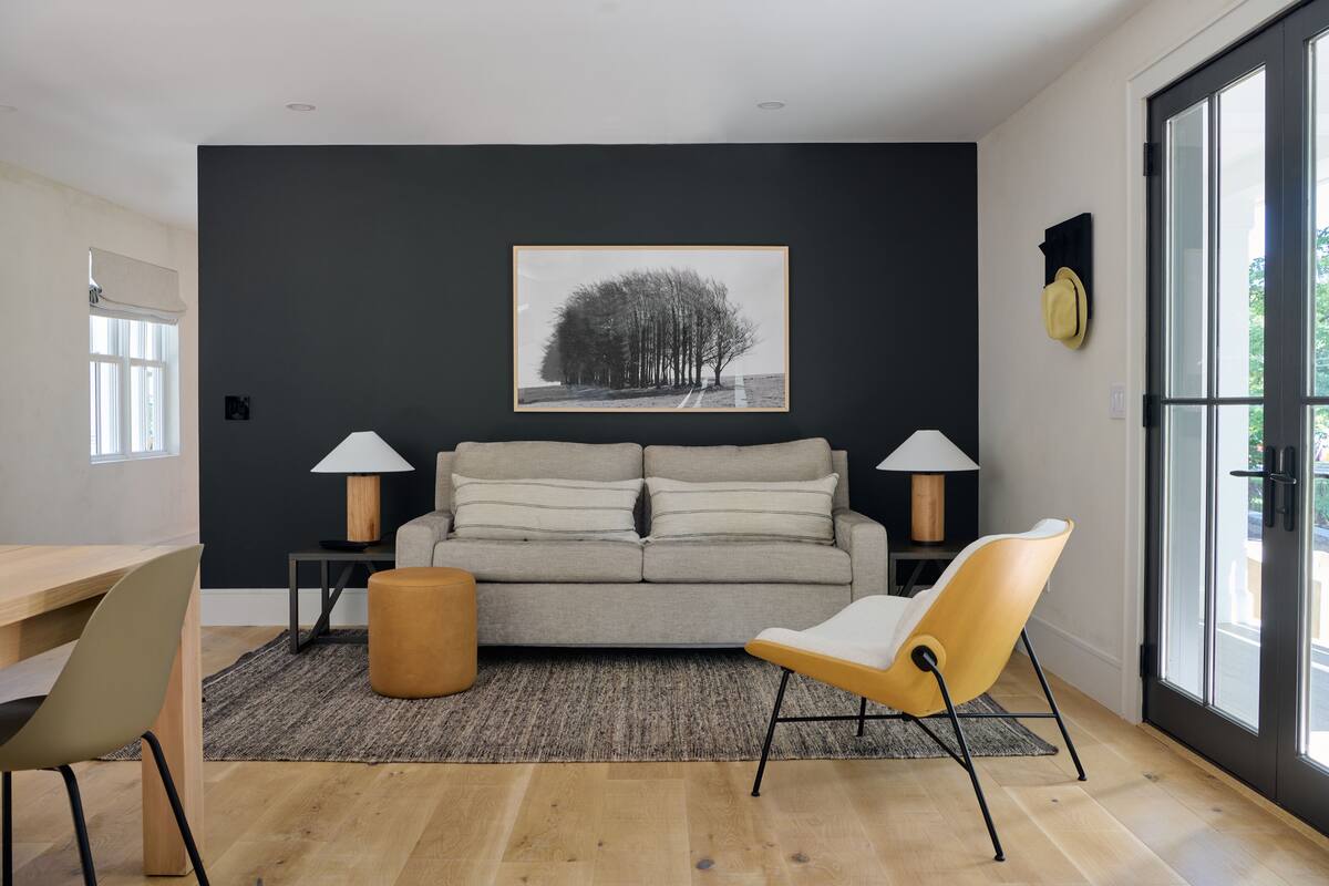 A modern living room with a grey sofa, two lamps, a yellow chair, and a rug.