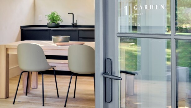 A modern kitchen with a dining area, a large window, and a view of the garden. - 9 Academy (Salisbury)