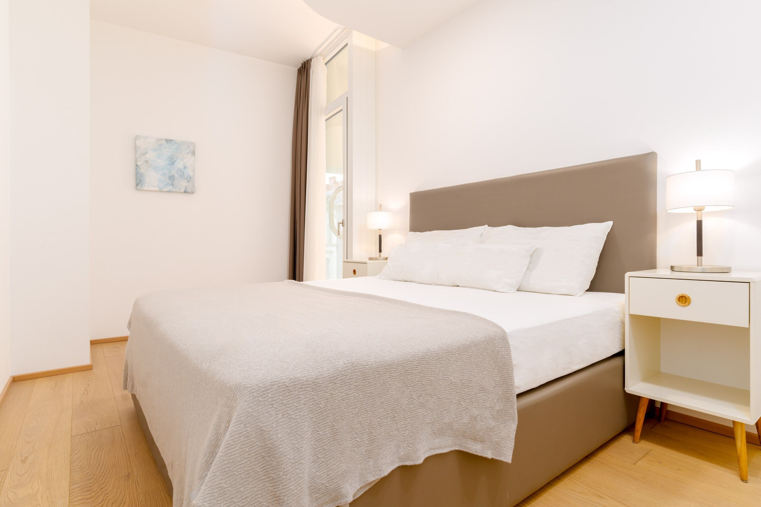 Een moderne hotelkamer met een groot bed, een nachtkastje met een lamp en een klein nachtkastje met een lamp.