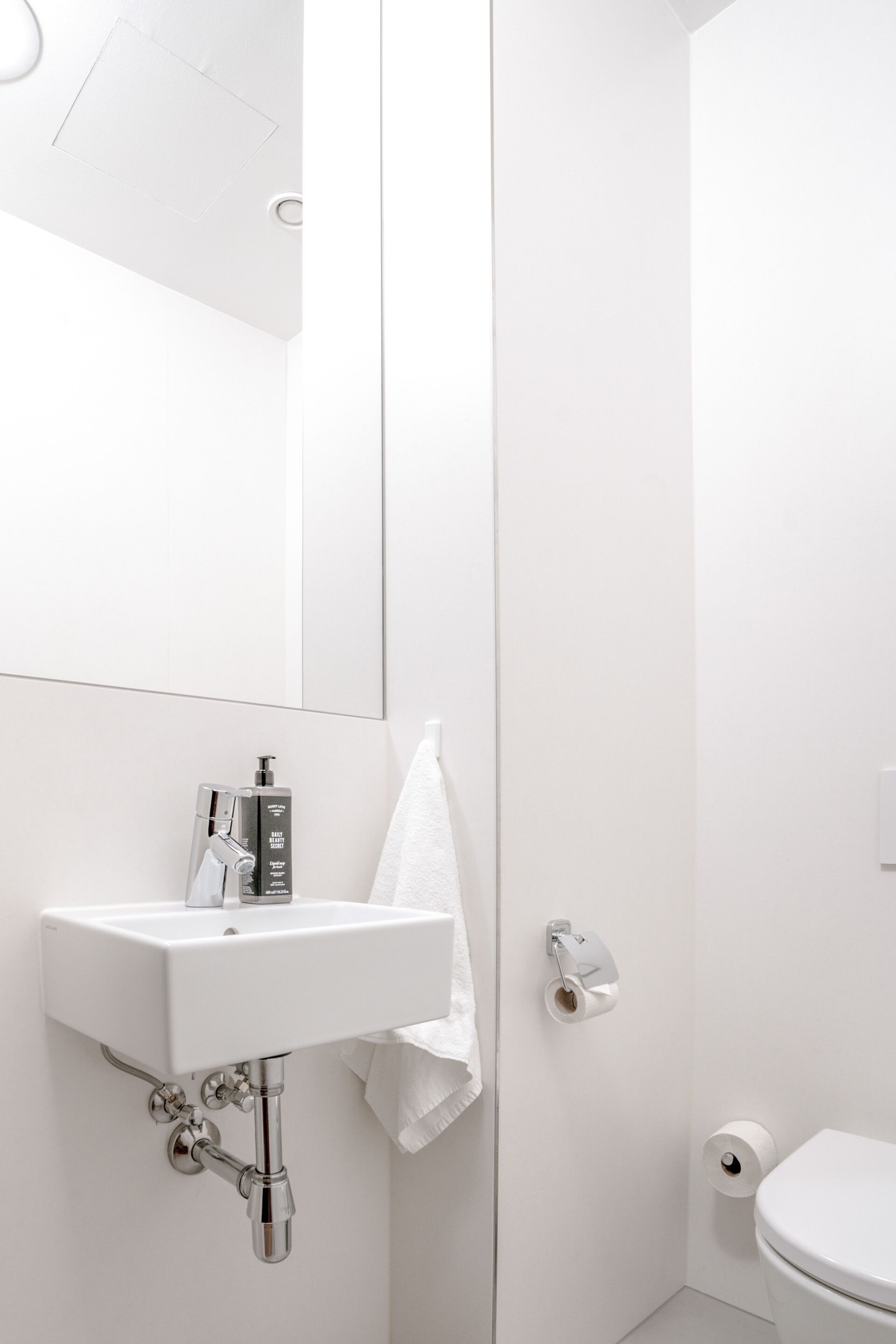 A modern bathroom with a white sink, mirror, and toilet.