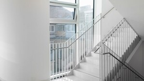 Un intérieur moderne avec un escalier, de grandes fenêtres et un plancher poli.