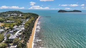 A coastal area with a beach, a pier, and a small island in the distance.