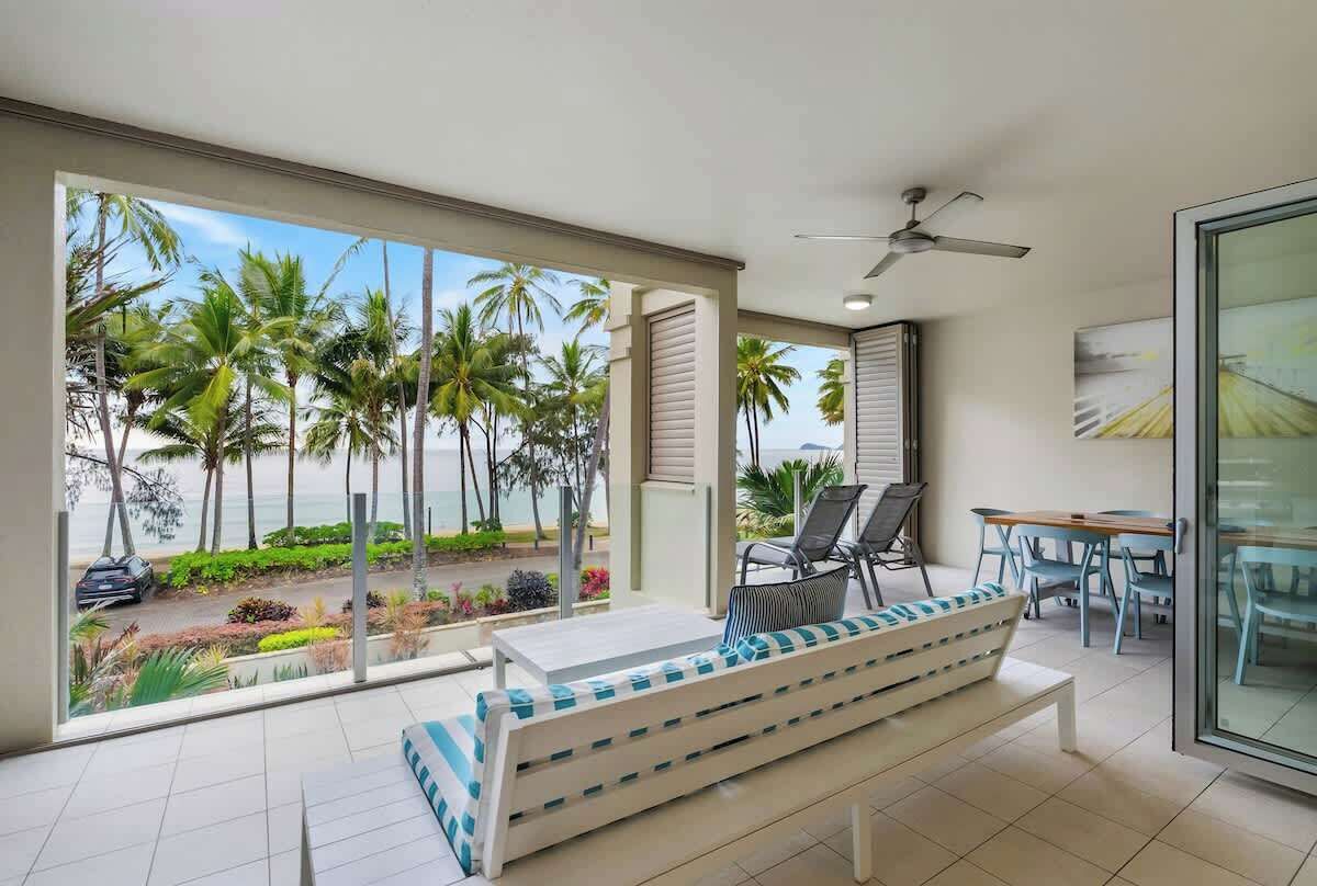 A modern room with a large balcony, a seating area with a bench, and a dining table with chairs.