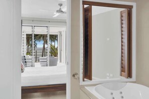 Un bagno moderno con uno specchio grande, una vasca e una porta scorrevole in vetro che dà su un balcone con mobili da esterno.