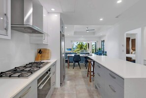 A modern kitchen with a gas stove, white cabinets, and a view to the dining area.