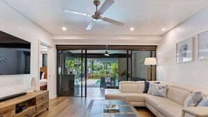 Un salon moderne avec un canapé, une table basse, un téléviseur et un ventilateur de plafond.