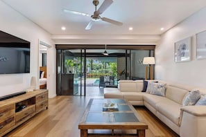 Un soggiorno moderno con divano, tavolino, televisore e ventilatore a soffitto.