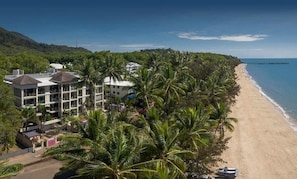 A beachfront hotel with multiple buildings, palm trees, and a pier extending into the ocean. - Opal Dreams—Your Gateway to Beachfront Bliss (Palm Cove)