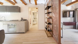 Una cocina moderna con vigas de madera, horno empotrado y un pasillo que lleva a un baño.