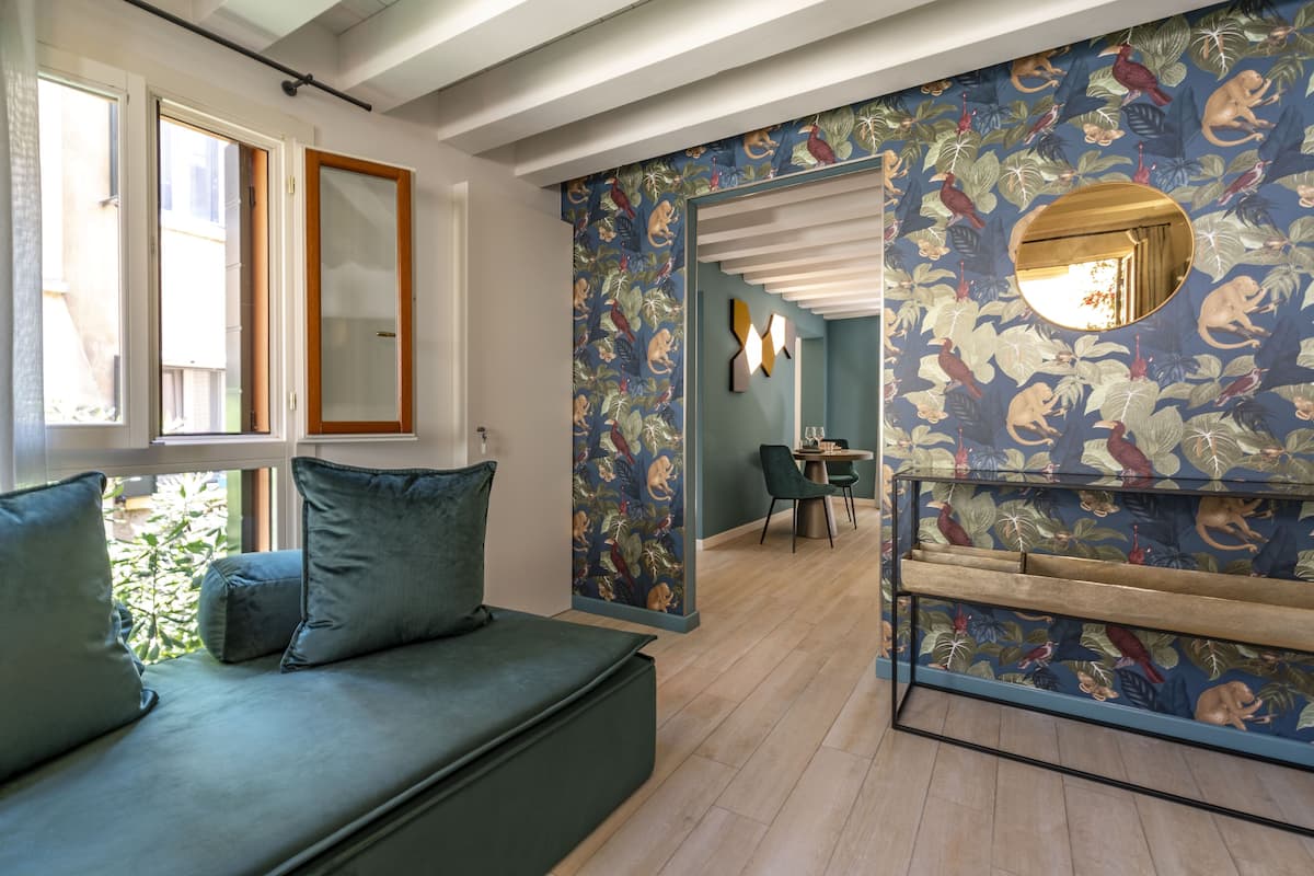 Un salon moderne avec un canapé vert, une table basse en bois et un mur orné d’un motif.