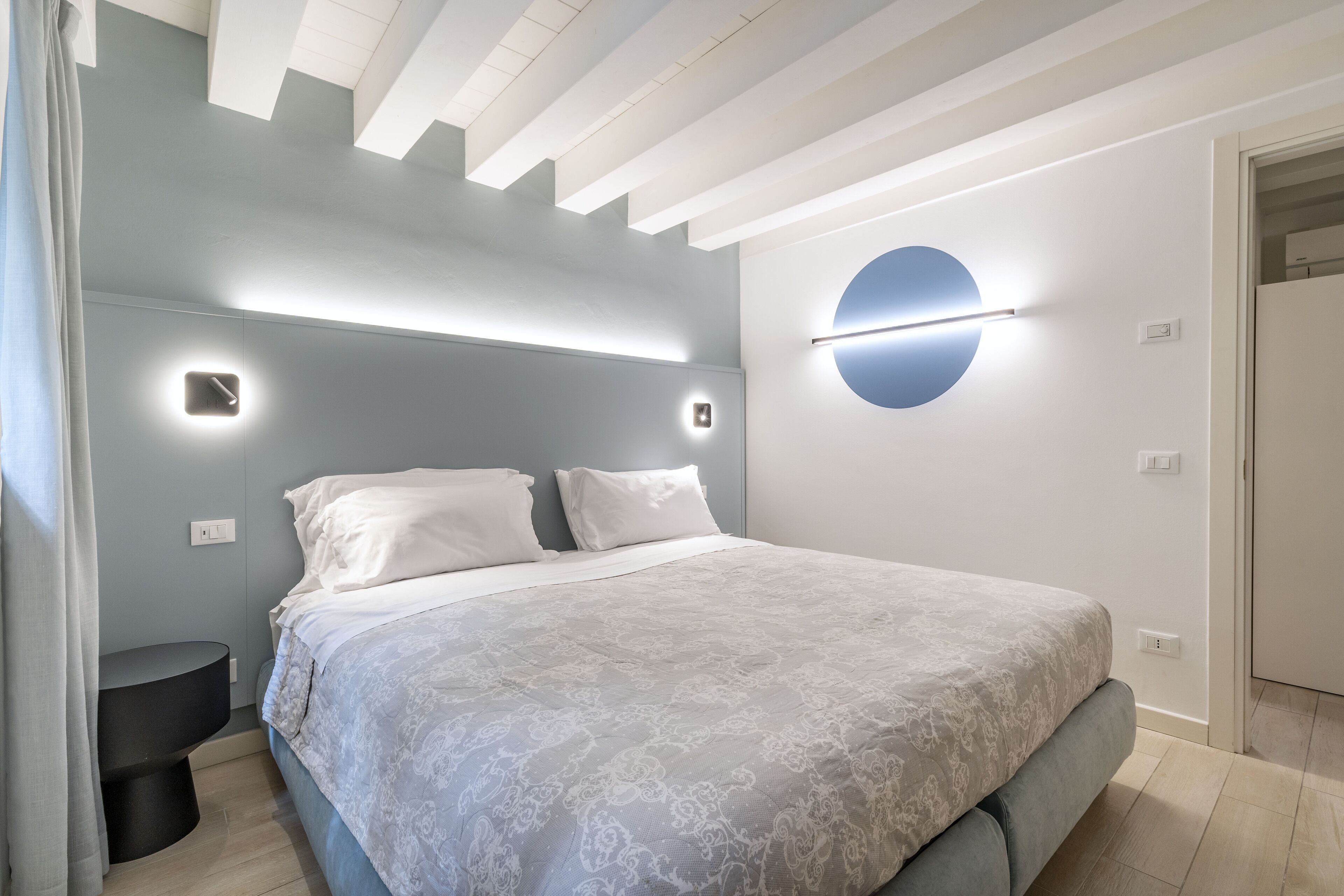 Un dormitorio moderno con una cama grande, cabecera integrada e iluminación empotrada.