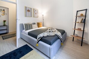 Een moderne slaapkamer met een bed, nachtkastjes, een vloerlamp en wanddecoratie.
