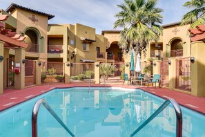 Zona de piscina de un hotel con una piscina cristalina, rodeada de balcones y palmeras.