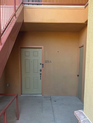 A building entrance with a door marked '121A' and a red metal staircase to the left.