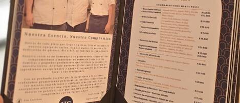 Menu aberto com foto de chefs e lista de pratos com preços.