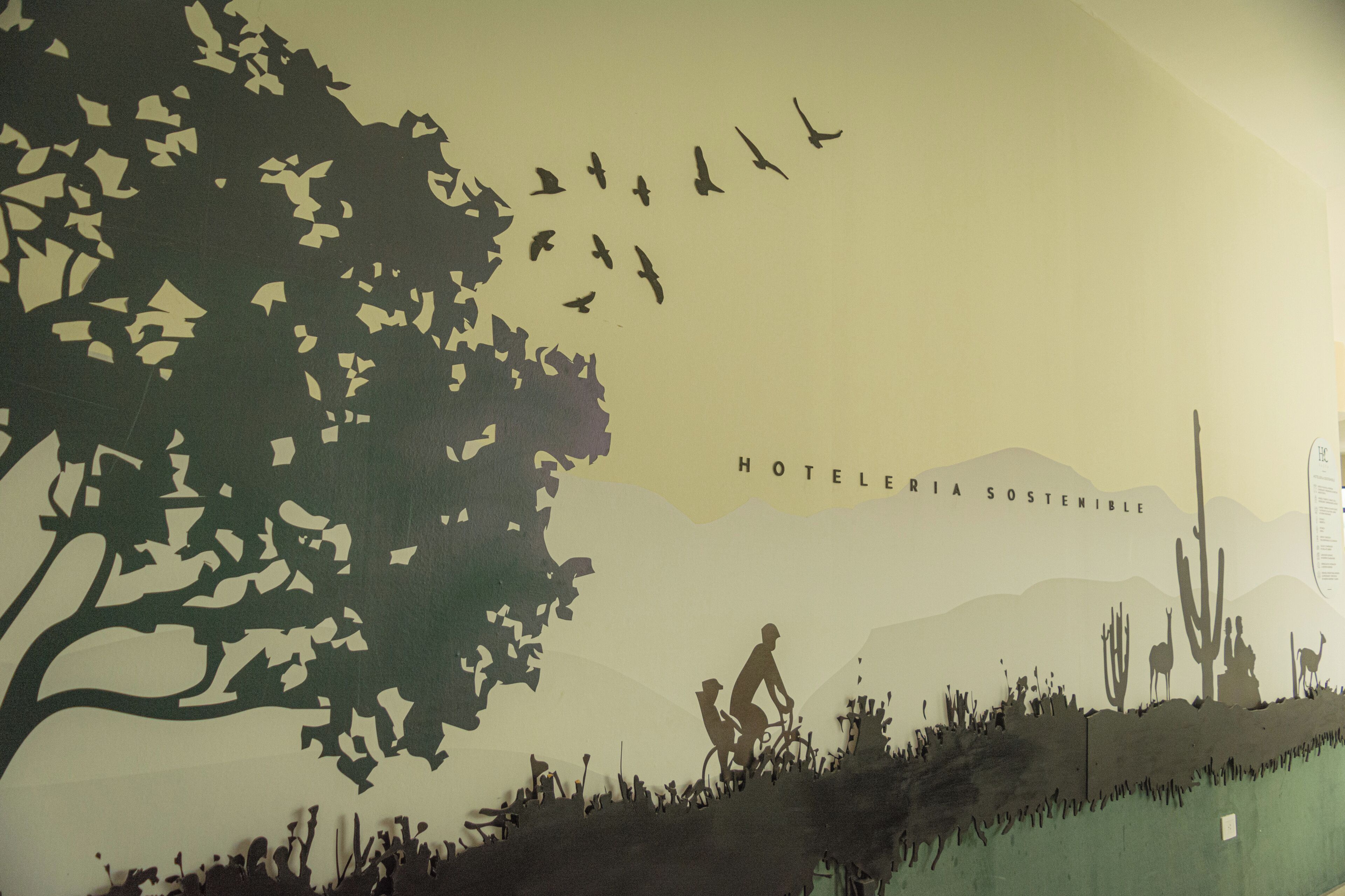 A poster with silhouettes of a tree, birds, a cyclist, and cacti, with the text "HOTELERIA SOSTENIBLE".
