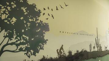 A poster with silhouettes of a tree, birds, a cyclist, and cacti, with the text "HOTELERIA SOSTENIBLE".