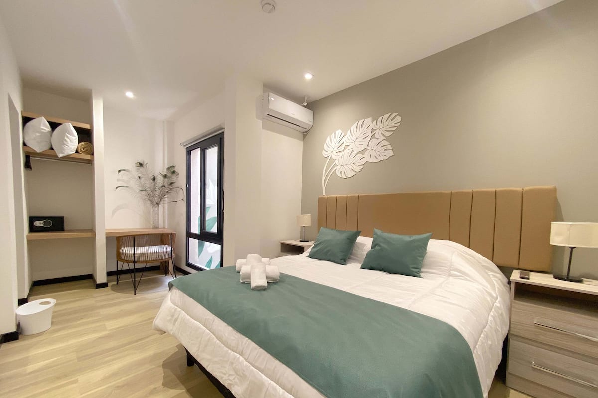 A modern bedroom with a large bed, a desk, and a chair.