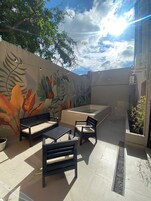 Un patio exterior con un mural, un jacuzzi y asientos.