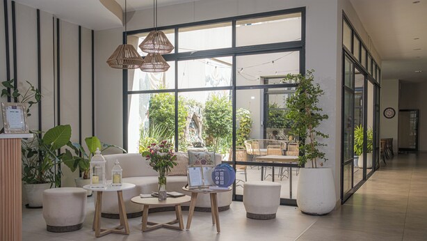 A modern indoor space with a sofa, two small tables, and potted plants. - Hotel Caseros Salta (Salta)