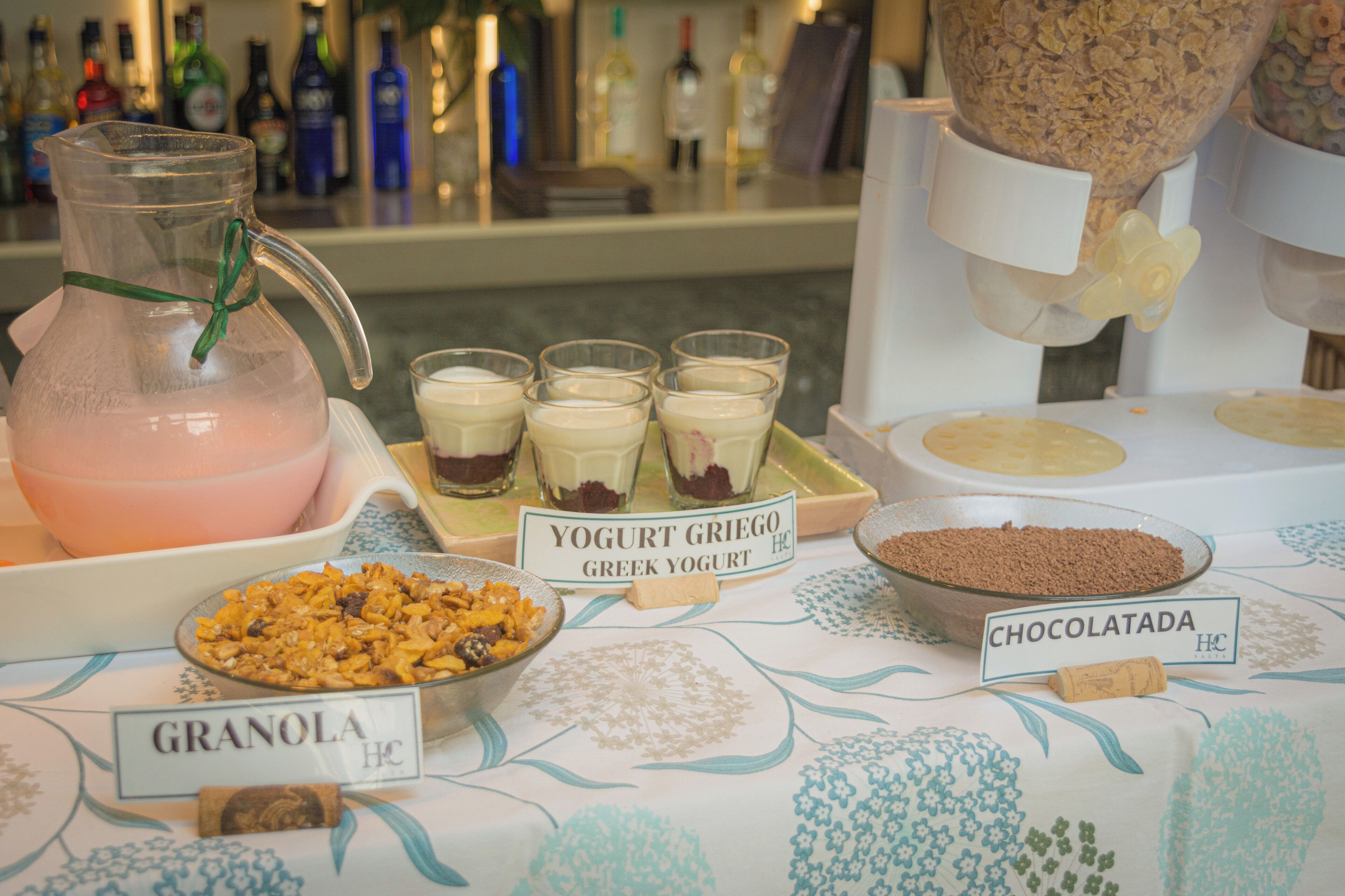Una mesa de buffet con alimentos identificados, incluyendo yogur, granola y chocolate.