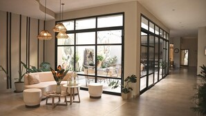 A spacious living area with a large window, a sofa, a coffee table, and hanging lamps. - Hotel Caseros Salta (Salta)