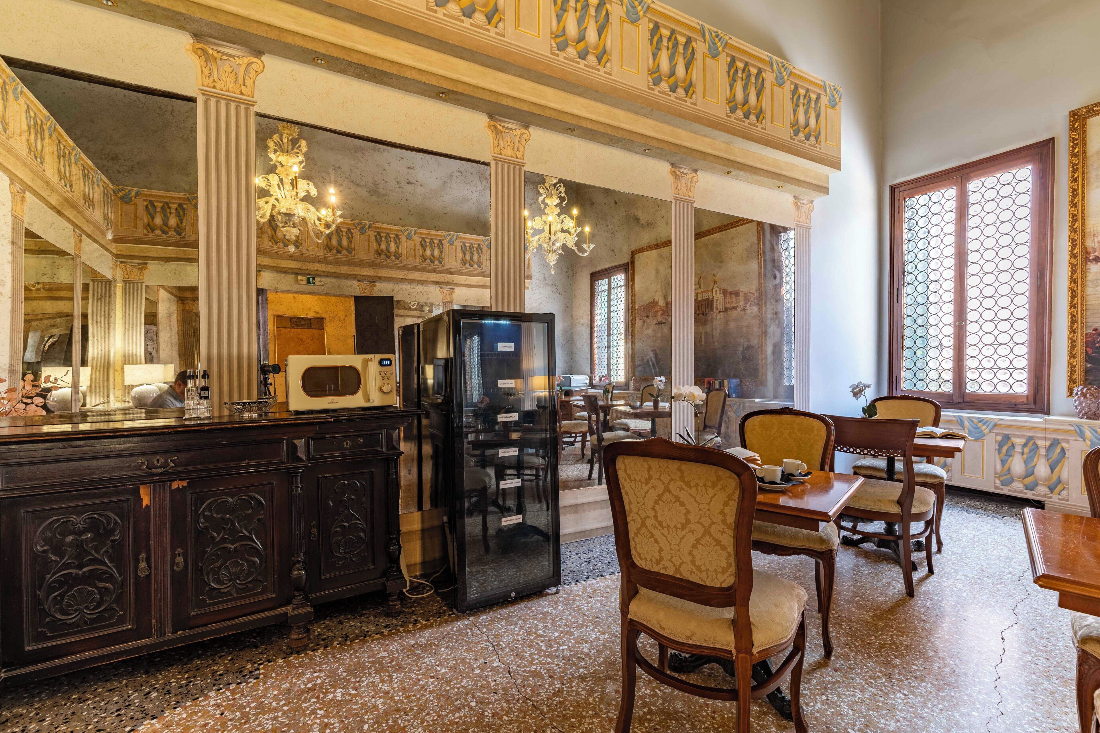 A dining area with a high ceiling, chandeliers, and a buffet setup.