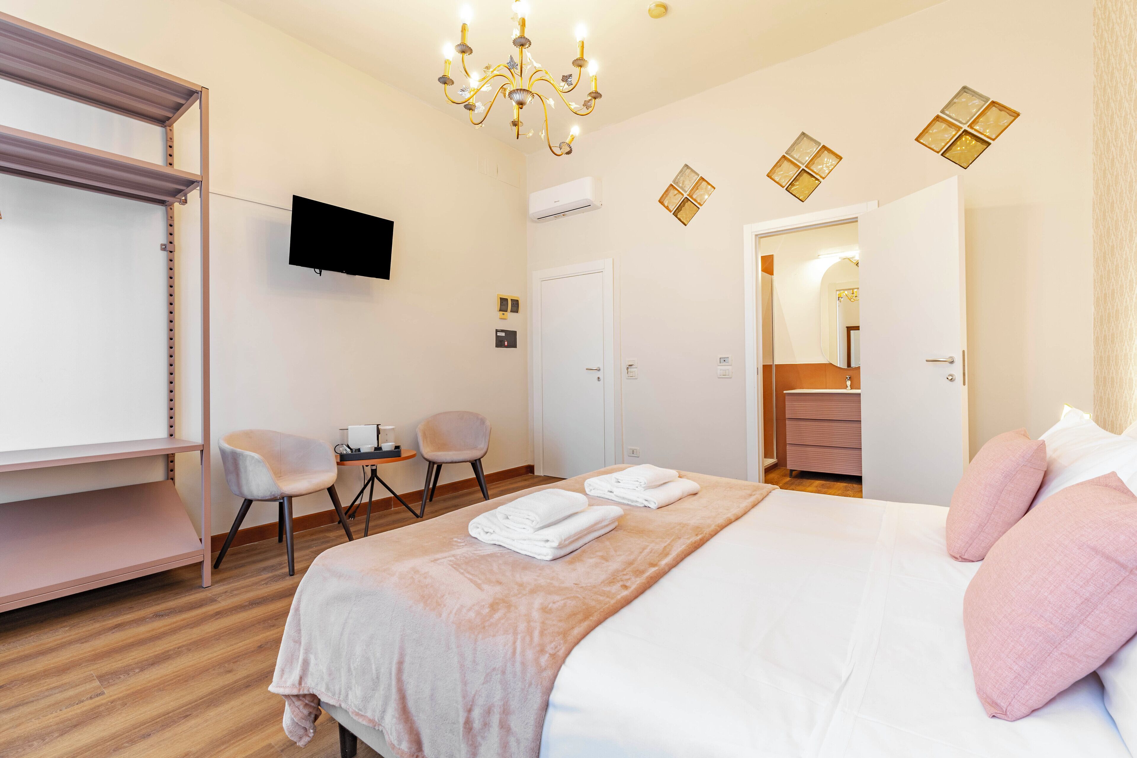 A hotel room with a bed, a desk, a chair, a television, and a wardrobe.