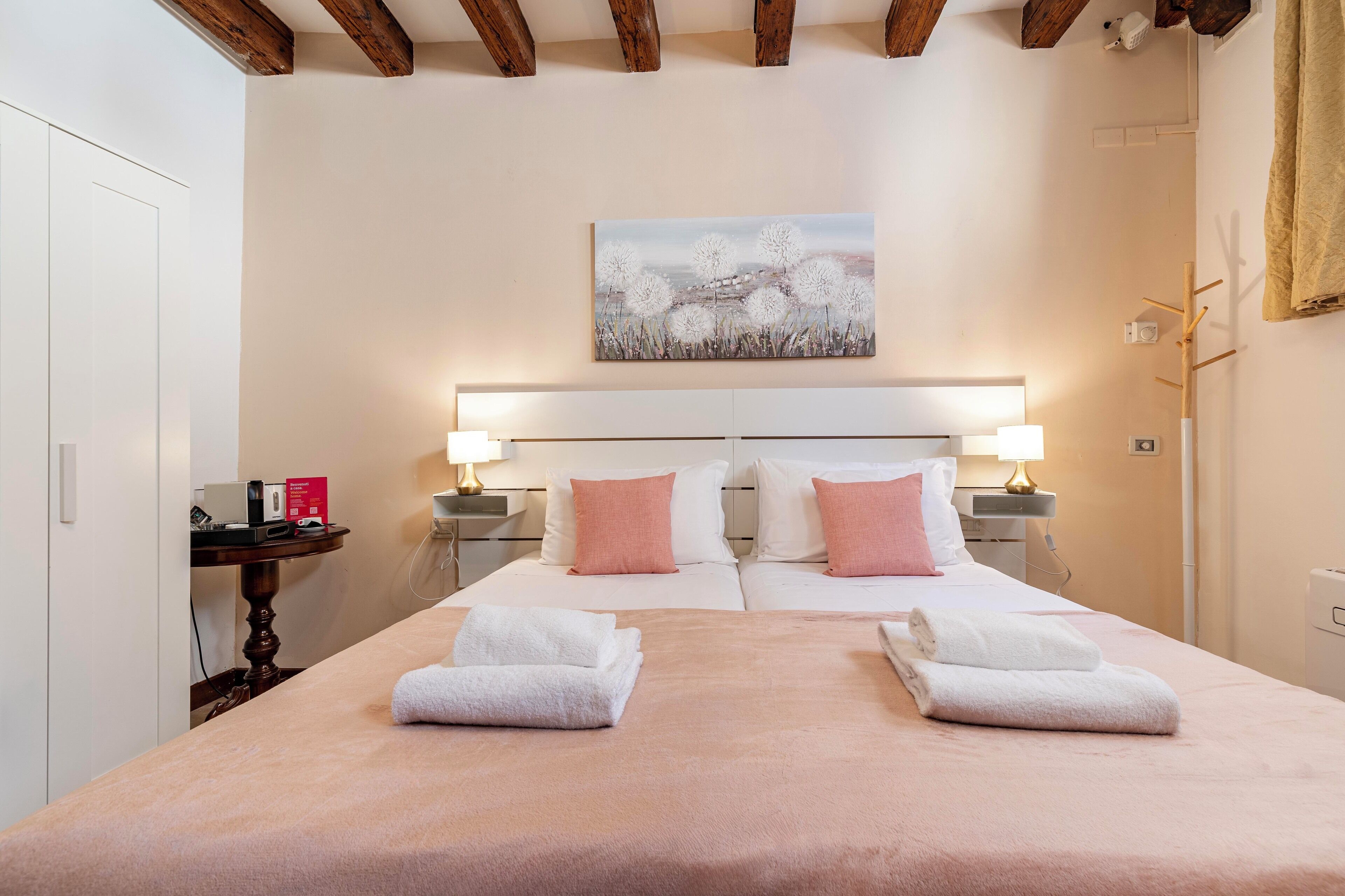 Une chambre d’hôtel avec un lit double, deux tables de chevet avec des lampes, un tableau au mur et un plafond en bois.