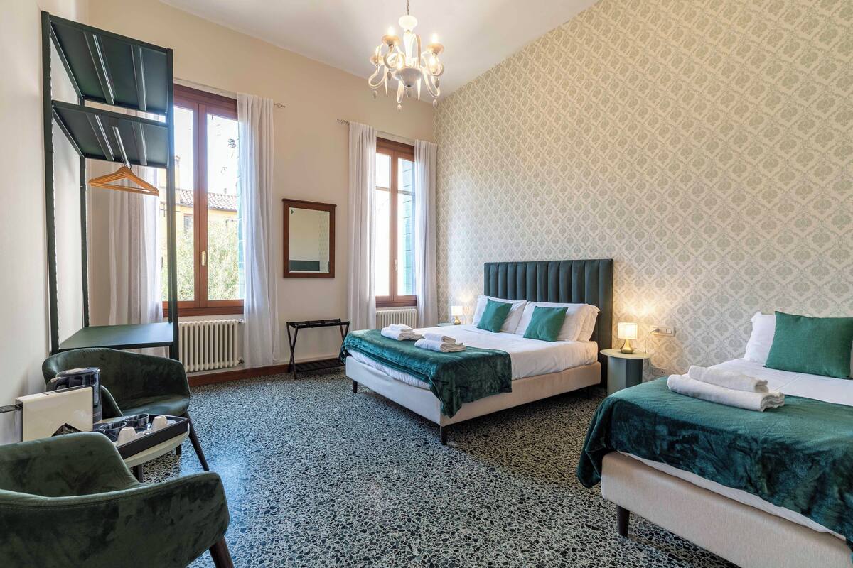 Ein Hotelzimmer mit Bett, Sessel, Schreibtisch, Heizkörper und Fenster.