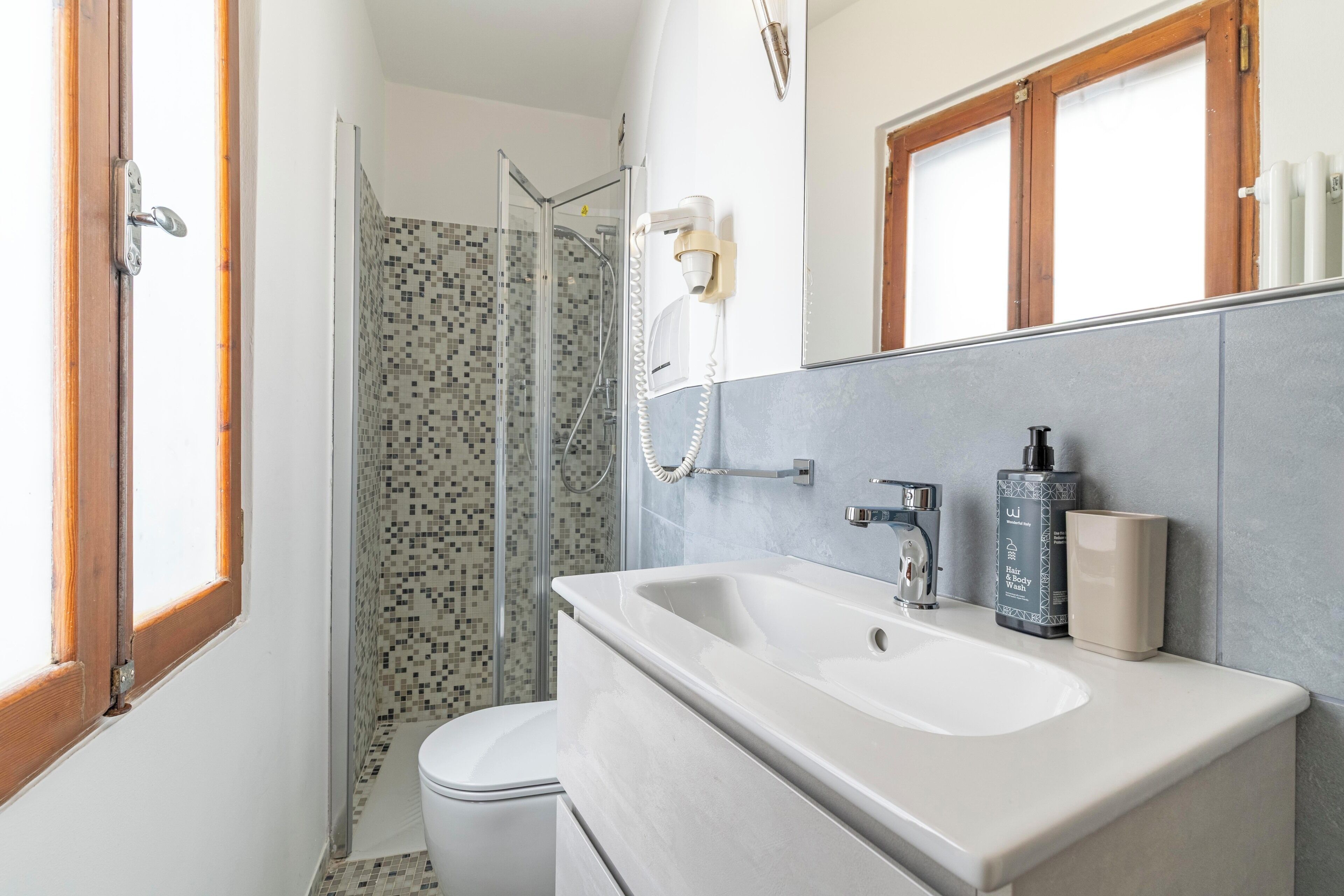 A bathroom with a shower, two sinks, and a mirror.