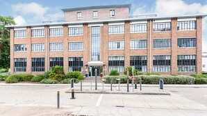 A multi-story brick building with large windows and a central entrance. - Travaal.com - FREE-WIFI-NETFLIX-PARKING - 2 Bedroom Apartment - Farnborough (Farnborough)