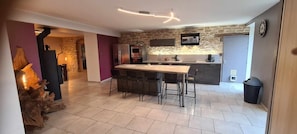 A modern kitchen with a central island, stone wall backsplash, and contemporary appliances.