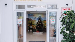 A hotel entrance with a Christmas tree and a mural of a mountain landscape. - 42 Da Lat Hotel (Xuan Huong - Da Lat)