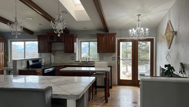 A spacious kitchen with high ceilings, wooden beams, and large windows. - Hot Tub & Mountain Views; Theatre; Sauna; Piano; Two tier deck; Kid’s room (Colorado Springs)