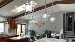 A spacious kitchen with a large marble island, wooden cabinets, and a chandelier. - Hot Tub & Mountain Views; Theatre; Sauna; Piano; Two tier deck; Kid’s room (Colorado Springs)