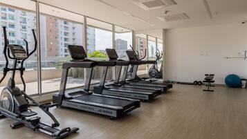Un gimnasio con cintas de correr, una bicicleta estática y una máquina de remo.